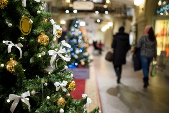 En julgran i ett centrum med två kvinnor som har handlat julklappar