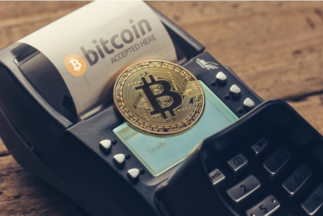 Ett bitcoinmynt som ligger på en betalkortsmaskin