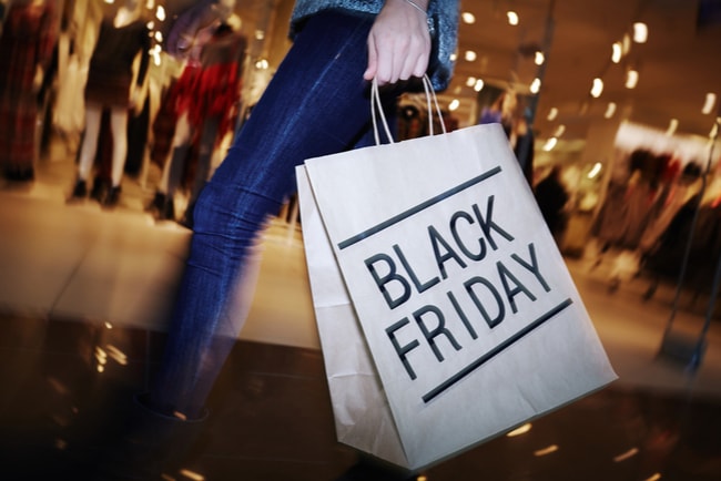 kvinna i shoppingcenter håller papperskasse med texten Black Friday på